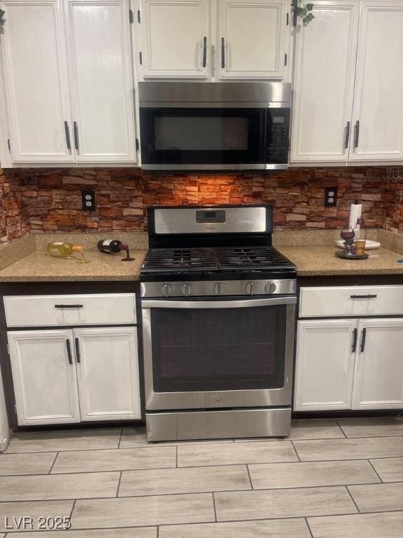 3128 Spring City Ave, North Las Vegas, NV 89081 - kitchen featuring appliances with stainless steel finishes, wood tiled floors, white cabinets, and decorative backsplash