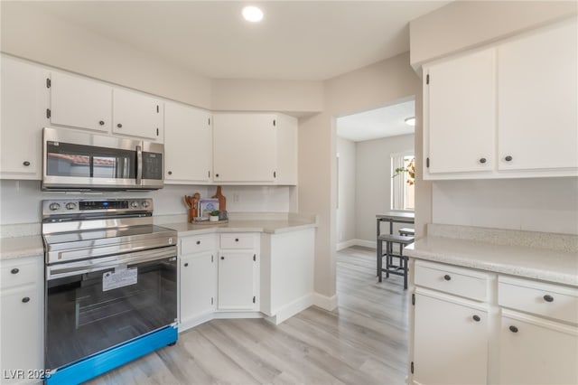3151 Soaring Gulls Dr Unit 2180, Las Vegas, NV 89128 - kitchen featuring appliances with stainless steel finishes, white cabinetry, light countertops, and light wood finished floors