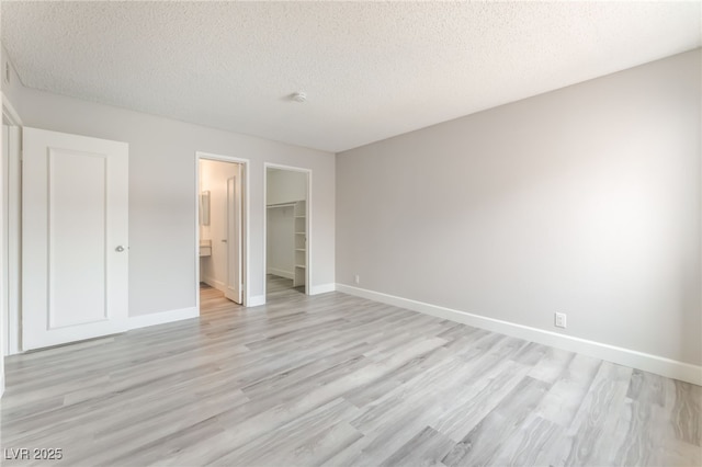 3151 Soaring Gulls Dr Unit 2180, Las Vegas, NV 89128 - unfurnished bedroom with a textured ceiling, light wood finished floors, a walk in closet, and a closet