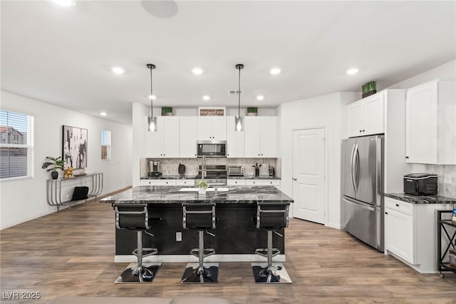 2833 Sangro Ct, Henderson, NV 89044 - kitchen with appliances with stainless steel finishes, a kitchen bar, recessed lighting, tasteful backsplash, and dark stone countertops