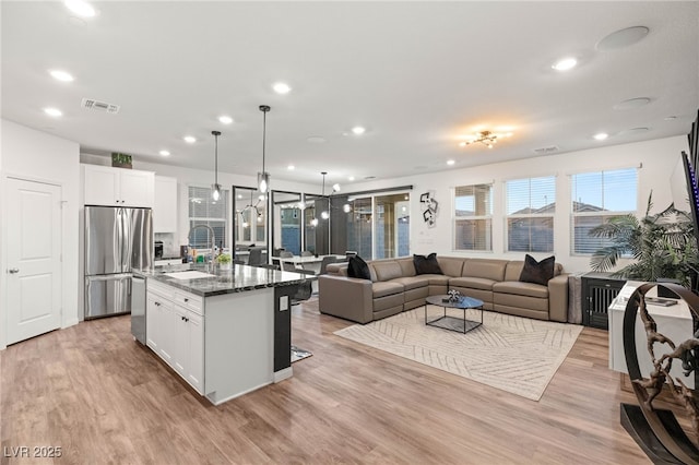 2833 Sangro Ct, Henderson, NV 89044 - kitchen featuring appliances with stainless steel finishes, open floor plan, recessed lighting, white cabinets, and light wood finished floors
