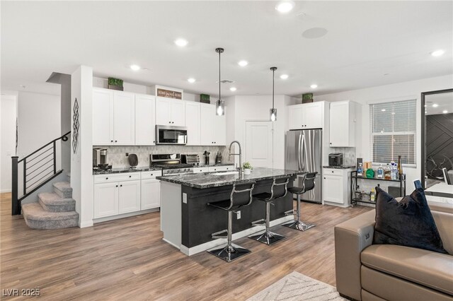 2833 Sangro Ct, Henderson, NV 89044 - kitchen featuring stainless steel appliances, open floor plan, a kitchen breakfast bar, tasteful backsplash, and a kitchen island with sink