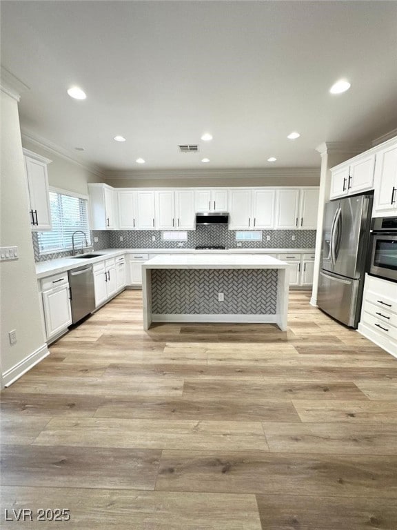 776 Tillis Pl, Las Vegas, NV 89138 - kitchen featuring appliances with stainless steel finishes, crown molding, white cabinetry, light wood finished floors, and backsplash