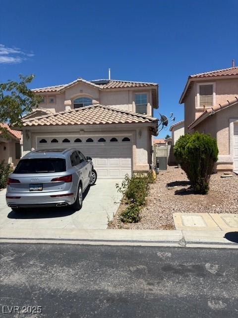 9940 Trailing Vine St, Las Vegas, NV 89183 - mediterranean / spanish-style home with a garage, a tiled roof, concrete driveway, and stucco siding