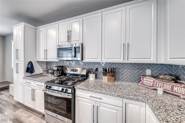 6335 Pacific Sky St, North Las Vegas, NV 89081 - kitchen with stainless steel appliances, white cabinetry, tasteful backsplash, and light stone counters