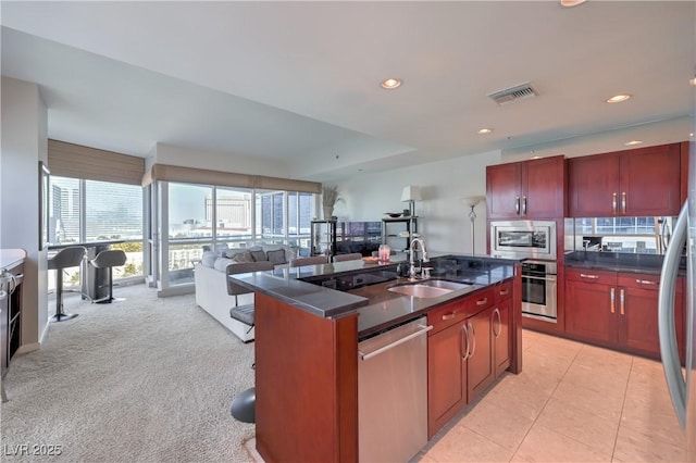 4575 Dean Martin Dr Unit 1112, Las Vegas, NV 89103 - kitchen with stainless steel appliances, dark countertops, dark brown cabinets, open floor plan, and a kitchen island with sink