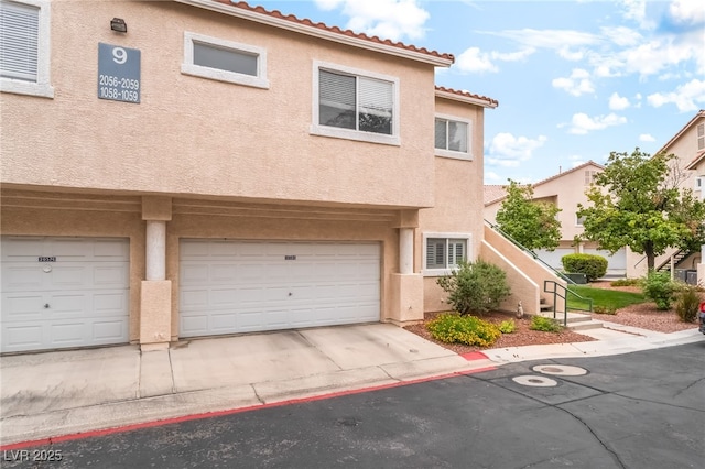 7450 S Eastern Ave Unit 1058, Las Vegas, NV 89123 - view of property featuring stucco siding, a garage, concrete driveway, and a tiled roof