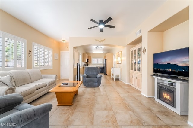 7450 S Eastern Ave Unit 1058, Las Vegas, NV 89123 - living room with a ceiling fan, arched walkways, a glass covered fireplace, and light tile patterned floors