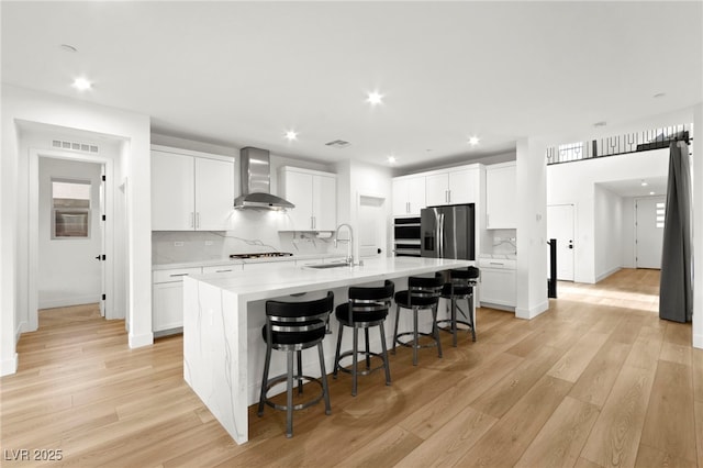 2004 Peaceful Mesa Ct, Henderson, NV 89052 - kitchen with wall chimney range hood, stainless steel fridge with ice dispenser, light wood finished floors, decorative backsplash, and recessed lighting