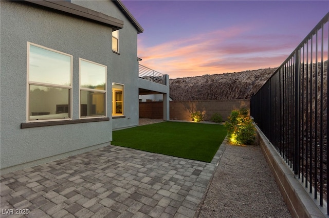 2004 Peaceful Mesa Ct, Henderson, NV 89052 - yard at dusk featuring a fenced backyard, a patio, and a balcony