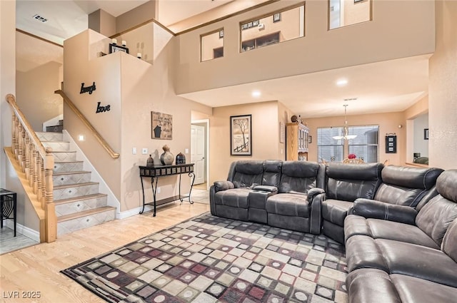 1325 Baychester Dr, Henderson, NV 89002 - living room featuring stairs, light wood-style flooring, a chandelier, and a high ceiling