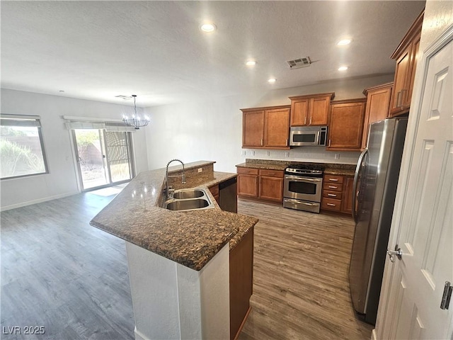 3544 Tack St, Las Vegas, NV 89122 - kitchen featuring appliances with stainless steel finishes, brown cabinets, a chandelier, dark wood-style floors, and recessed lighting