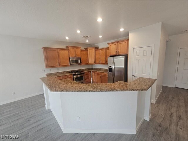 3544 Tack St, Las Vegas, NV 89122 - kitchen featuring stainless steel appliances, light wood finished floors, brown cabinets, stone countertops, and recessed lighting
