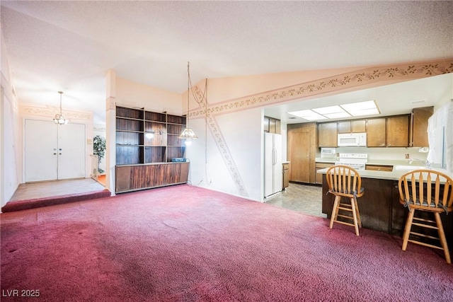 6513 Hyde Ave, Las Vegas, NV 89107 - kitchen featuring white appliances, vaulted ceiling, light carpet, a peninsula, and light countertops