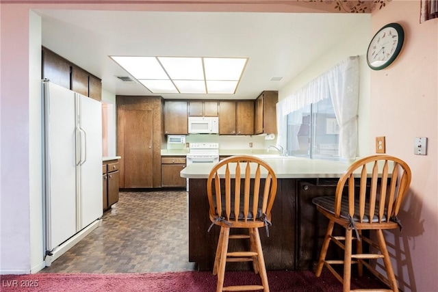 6513 Hyde Ave, Las Vegas, NV 89107 - kitchen featuring white appliances, a peninsula, light countertops, and a kitchen bar