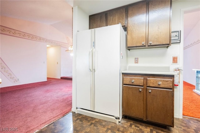 6513 Hyde Ave, Las Vegas, NV 89107 - kitchen featuring freestanding refrigerator, light countertops, dark colored carpet, and vaulted ceiling