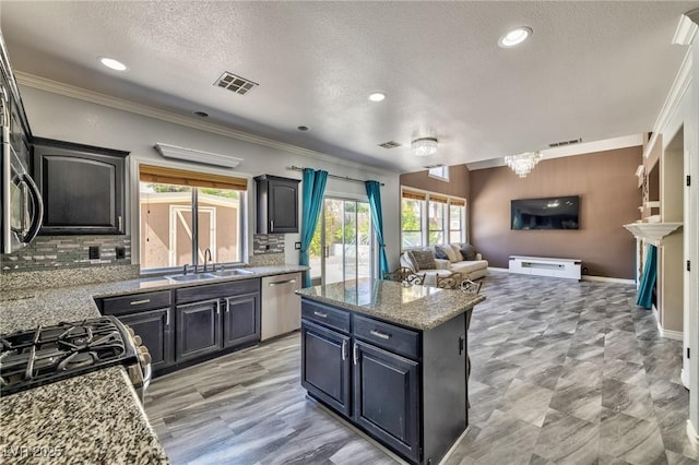 3525 Dover Bay St, Las Vegas, NV 89129 - kitchen with appliances with stainless steel finishes, a kitchen island, open floor plan, tasteful backsplash, and a textured ceiling