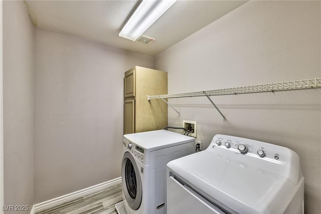 3525 Dover Bay St, Las Vegas, NV 89129 - laundry room featuring washing machine and dryer, light wood finished floors, and cabinet space