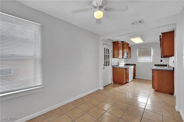 75 N 27th St, Las Vegas, NV 89101 - kitchen featuring white range with electric stovetop, light tile patterned floors, stainless steel microwave, a ceiling fan, and dark countertops
