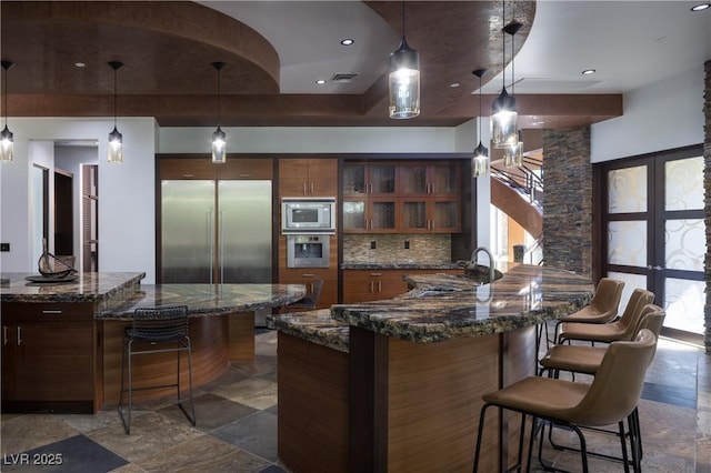 17 Soaring Bird Ct, Las Vegas, NV 89135 - kitchen with built in appliances, a kitchen breakfast bar, glass insert cabinets, brown cabinetry, and decorative backsplash