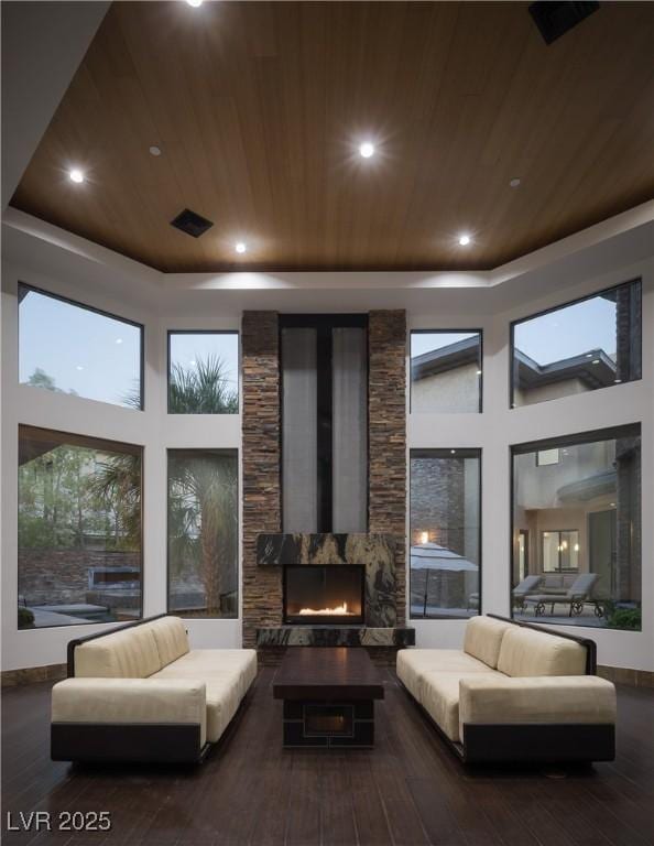 17 Soaring Bird Ct, Las Vegas, NV 89135 - living room featuring wood ceiling, hardwood / wood-style flooring, a towering ceiling, a stone fireplace, and a tray ceiling