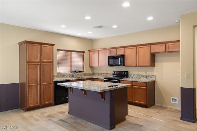 5338 Lignum Ave, Pahrump, NV 89061 - kitchen with black appliances, a center island, brown cabinetry, and recessed lighting