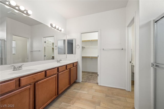 5338 Lignum Ave, Pahrump, NV 89061 - full bathroom featuring double vanity, wood finished floors, a shower with shower door, and a walk in closet