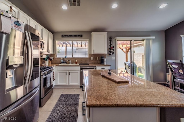 5028 Crying Heart St, North Las Vegas, NV 89031 - kitchen featuring stainless steel appliances, white cabinets, recessed lighting, a center island, and decorative backsplash