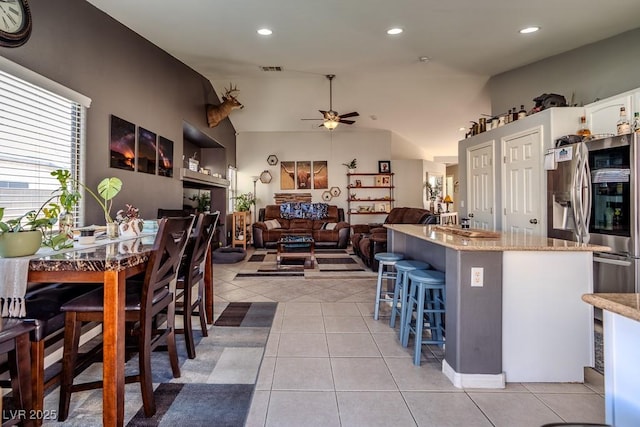 5028 Crying Heart St, North Las Vegas, NV 89031 - kitchen with ceiling fan, light tile patterned floors, a breakfast bar area, stainless steel refrigerator with ice dispenser, and lofted ceiling