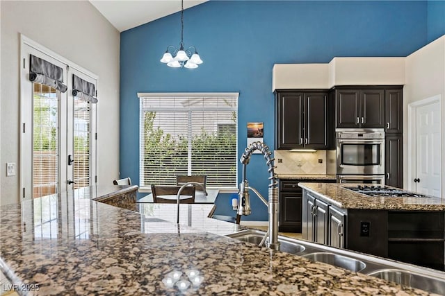 2010 Catalina Marie Ave, Henderson, NV 89074 - kitchen featuring high vaulted ceiling, a chandelier, stainless steel appliances, dark cabinets, and decorative light fixtures