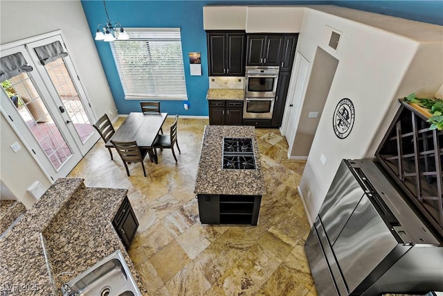 2010 Catalina Marie Ave, Henderson, NV 89074 - kitchen with double oven, a chandelier, dark cabinets, light stone counters, and decorative light fixtures