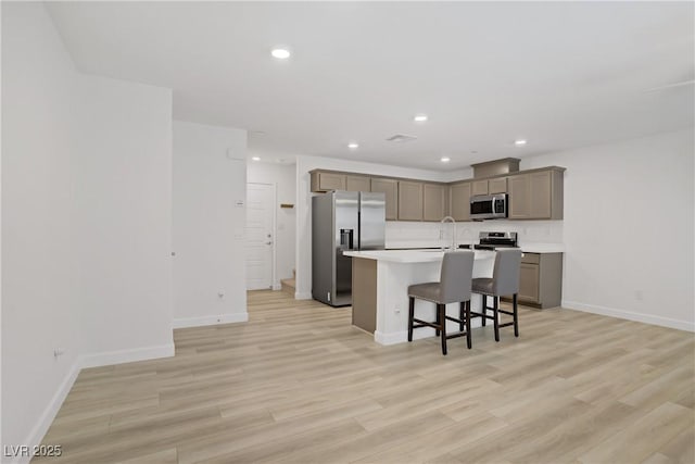 3621 Arcadian Sea St, Las Vegas, NV 89106 - kitchen featuring stainless steel appliances, a kitchen breakfast bar, a kitchen island with sink, light countertops, and recessed lighting
