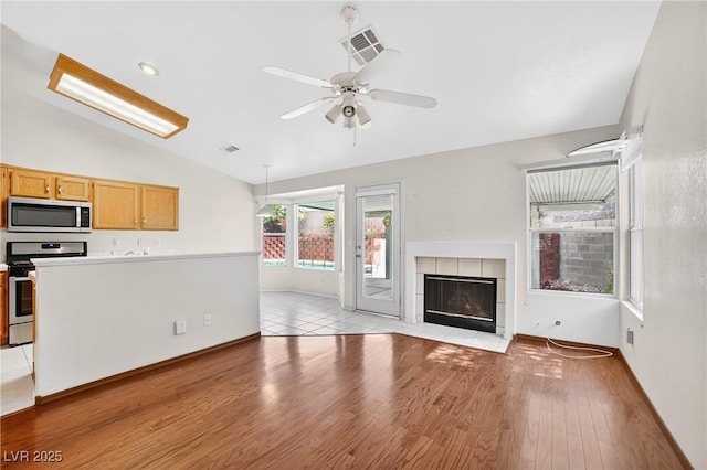 114 Tamarack Dr, Henderson, NV 89002 - unfurnished living room featuring lofted ceiling, ceiling fan, light wood-type flooring, and a tiled fireplace