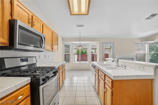 114 Tamarack Dr, Henderson, NV 89002 - kitchen with appliances with stainless steel finishes, tile counters, light tile patterned floors, an island with sink, and decorative light fixtures