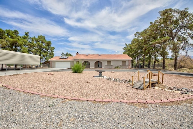 1050 Morgan Ln, Pahrump, NV 89060 - view of front of property with a chimney, driveway, stucco siding, roof mounted solar panels, and a tile roof