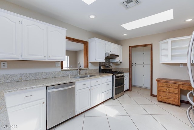 1050 Morgan Ln, Pahrump, NV 89060 - kitchen featuring stainless steel appliances, a skylight, under cabinet range hood, white cabinets, and light tile patterned flooring