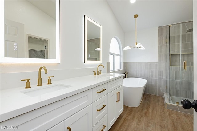 2107 Fountain Springs Dr, Henderson, NV 89074 - bathroom with tile walls, a soaking tub, double vanity, wood finished floors, and a shower with door