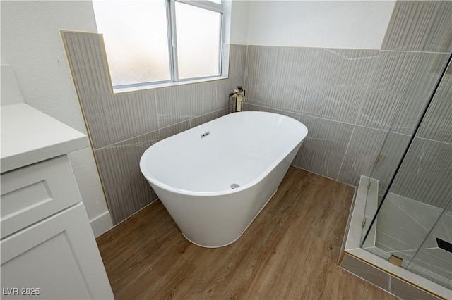 2107 Fountain Springs Dr, Henderson, NV 89074 - bathroom featuring wood finished floors, a freestanding tub, vanity, a walk in shower, and tile walls