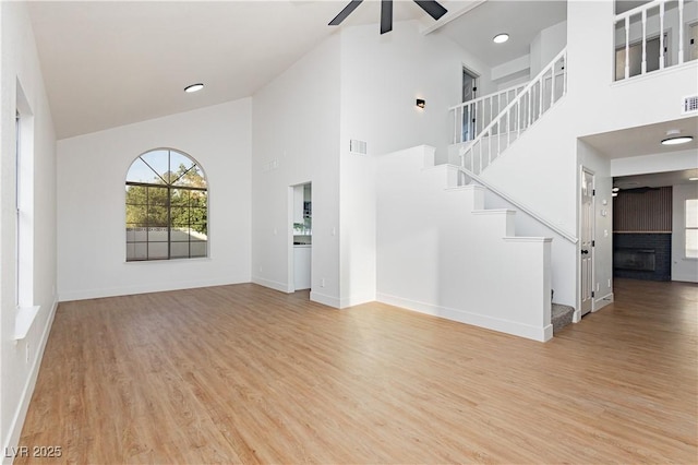 2107 Fountain Springs Dr, Henderson, NV 89074 - unfurnished living room with ceiling fan, wood finished floors, high vaulted ceiling, stairs, and a fireplace