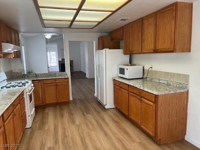 9600 Pacific View Dr, Las Vegas, NV 89117 - kitchen featuring white appliances, light wood finished floors, brown cabinets, and under cabinet range hood