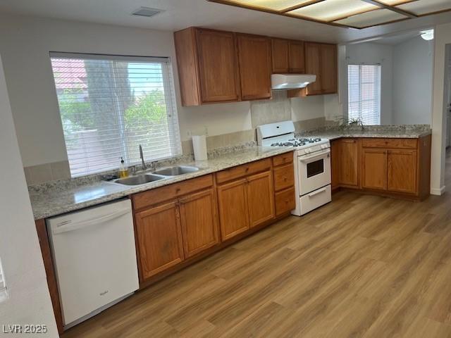 9600 Pacific View Dr, Las Vegas, NV 89117 - kitchen with white appliances, under cabinet range hood, light wood-type flooring, brown cabinetry, and light stone counters