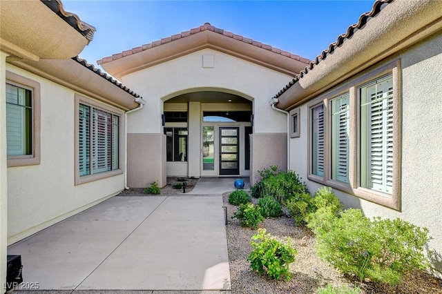 33 Hassayampa Trl, Henderson, NV 89052 - doorway to property featuring stucco siding, a tile roof, and a patio area