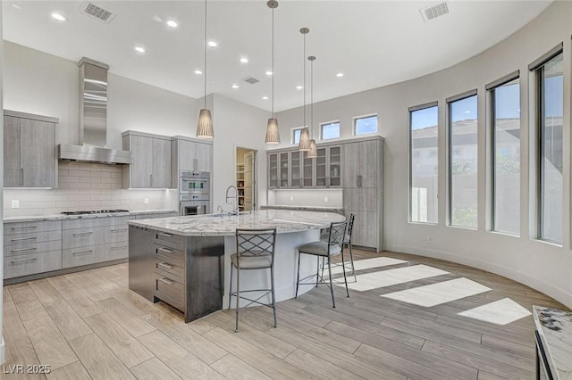 33 Hassayampa Trl, Henderson, NV 89052 - kitchen with gray cabinets, wall chimney exhaust hood, modern cabinets, stainless steel appliances, and a spacious island