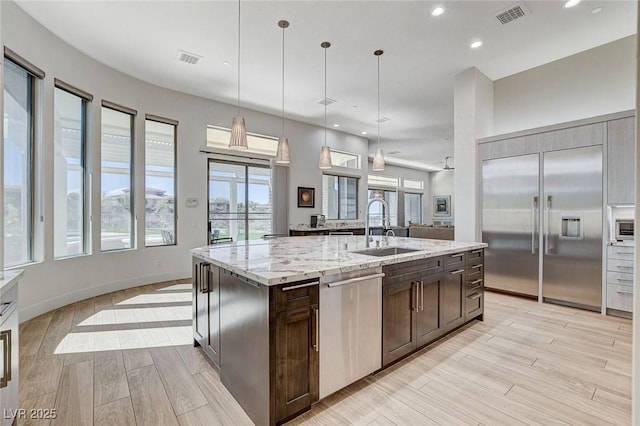 33 Hassayampa Trl, Henderson, NV 89052 - kitchen with appliances with stainless steel finishes, dark brown cabinetry, recessed lighting, light stone counters, and light wood-type flooring