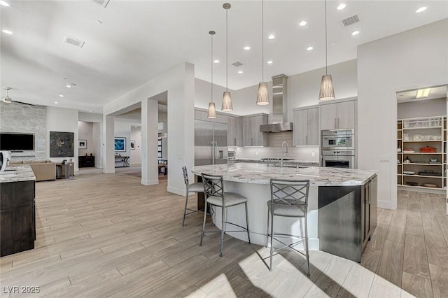 33 Hassayampa Trl, Henderson, NV 89052 - kitchen with wall chimney range hood, stainless steel appliances, modern cabinets, light wood-style floors, and a spacious island