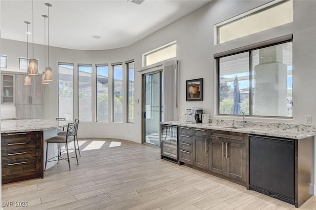 33 Hassayampa Trl, Henderson, NV 89052 - kitchen with wine cooler, a kitchen bar, light stone counters, light wood-type flooring, and dark brown cabinetry
