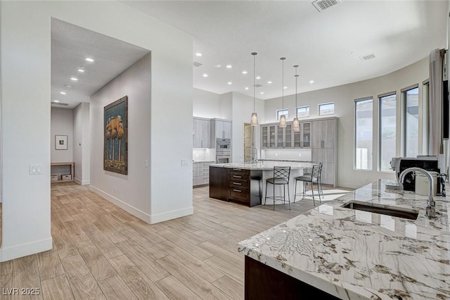 33 Hassayampa Trl, Henderson, NV 89052 - kitchen with a breakfast bar, light wood-type flooring, a large island with sink, glass insert cabinets, and recessed lighting