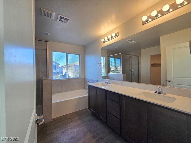 5817 Bonita Rose St, Las Vegas, NV 89113 - bathroom featuring wood finished floors, a shower stall, a bath, double vanity, and a spacious closet
