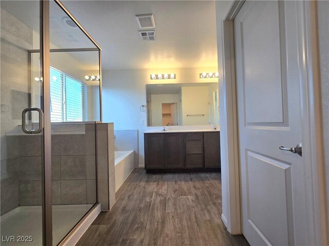 5817 Bonita Rose St, Las Vegas, NV 89113 - bathroom featuring wood finished floors, double vanity, a garden tub, and a shower stall