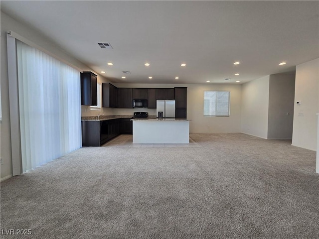 5817 Bonita Rose St, Las Vegas, NV 89113 - kitchen with stainless steel fridge, black microwave, open floor plan, light colored carpet, and recessed lighting
